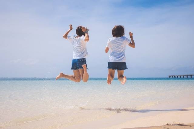 砂浜でジャンプをするいかにもリア充な双子コーデの二人組の画像｜おしゃれなフリー写真素材：GIRLY DROP (49113)